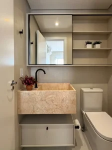 Lavabo com cuba em mármore rosa, espelho com nicho e metais pretos, em apartamento reformado no Tatuapé. Projeto Luvin Arquitetura, obra Siolam Engenharia