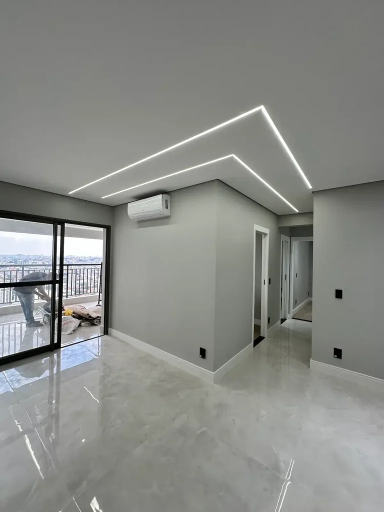 Sala de apartamento reformado em São Paulo com iluminação LED linear no teto e piso porcelanato polido - Siolam Engenharia