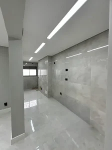 Cozinha de apartamento reformada com porcelanato polido nas paredes e iluminação linear no teto - Siolam Engenharia