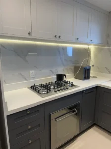Cozinha reformada com armários provençais branco e cinza, revestimento marmorizado e fita de LED - Siolam Engenharia